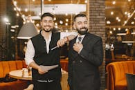 Two smiling businessmen posing in a stylish restaurant with warm lighting.